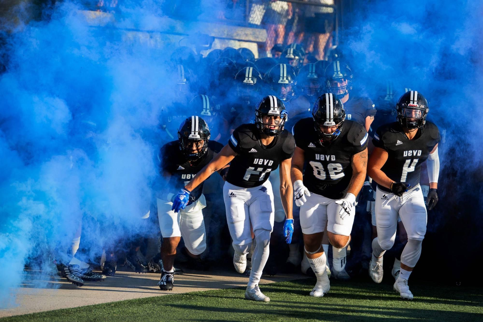 GVSU Football players run onto the field with blue smoke